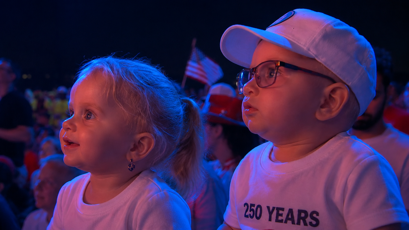 Babies watching the 250 years celebration under red and blue stage light